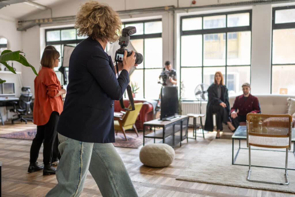 Photographer with camera capturing team members seated in modern office setting during a company branding photoshoot